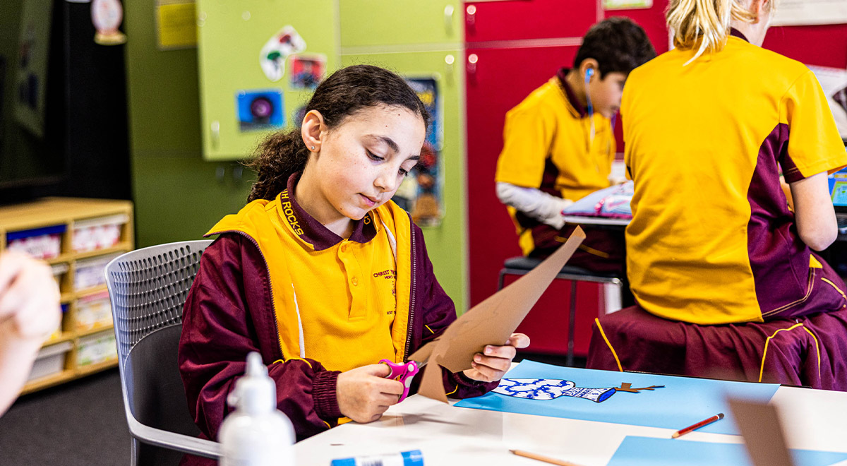 Student cutting paper at Christ the King Catholic Primary School North Rocks