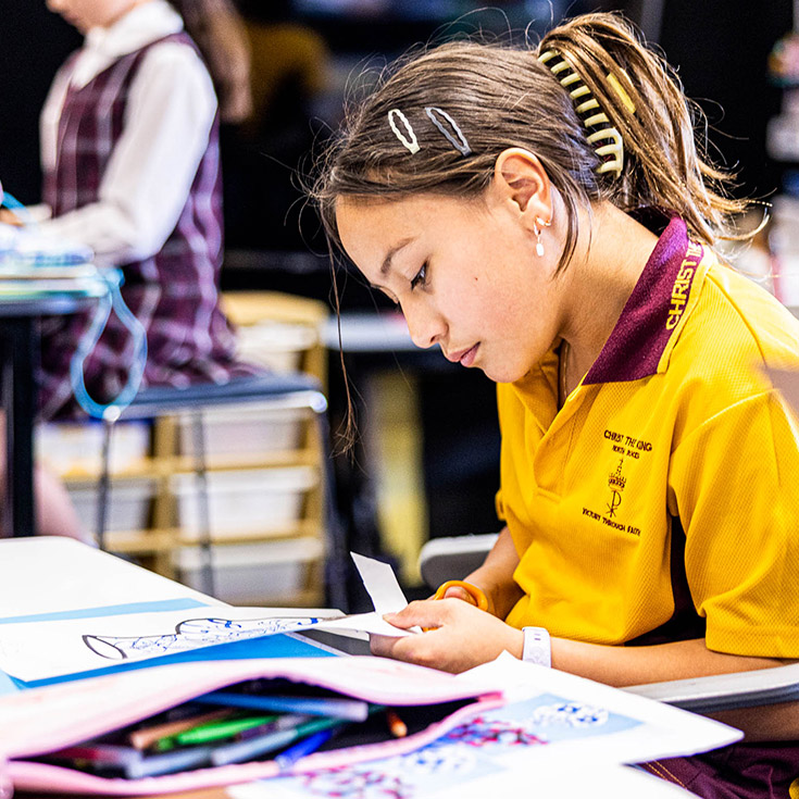 Student cutting paper at Christ the King Catholic Primary School North Rocks