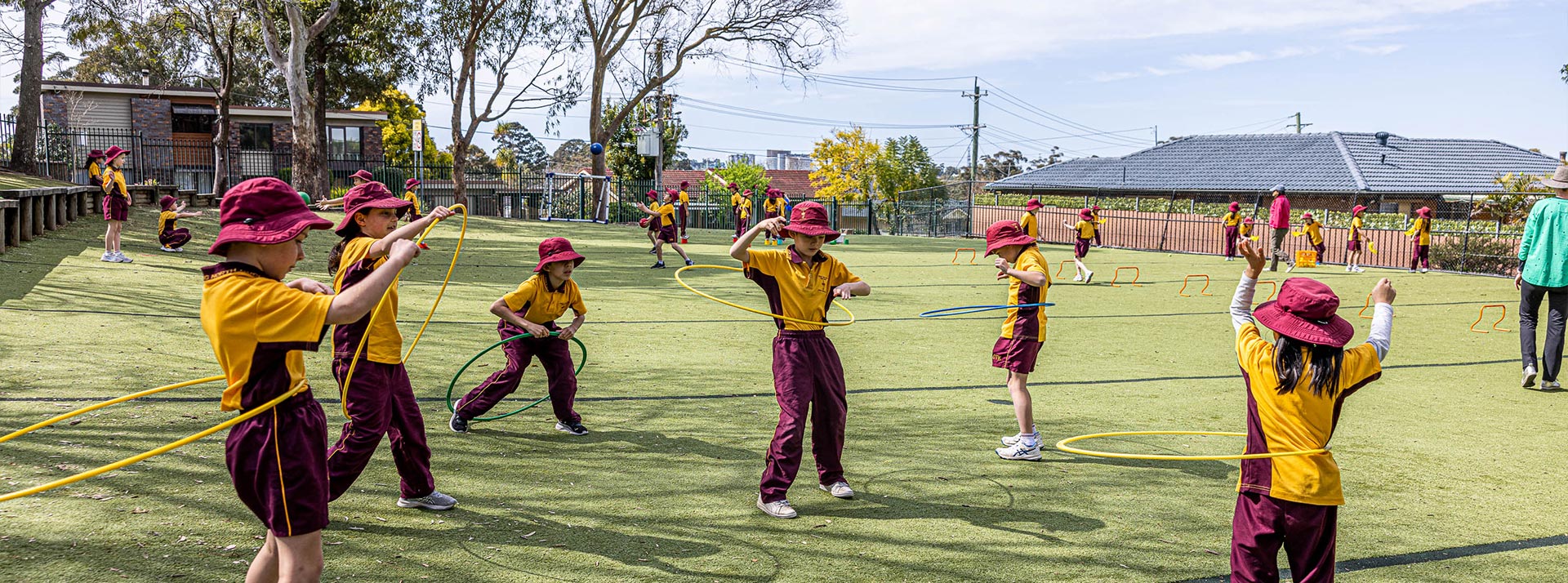 Christ the King North Rocks students playing on outdoor sports field. They are hula-hooping.